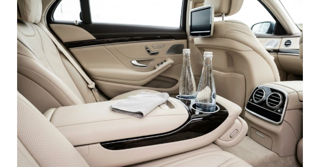 Beige luxury sedan rear seat interior with water bottles and comfort amenities
