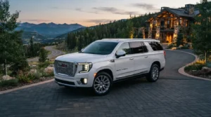 Premium white GMC Yukon Denali executive SUV parked on a driveway in front of a luxury lodge