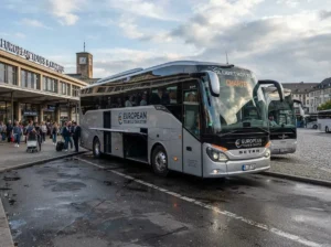 A modern grey luxury coach bus parked at a terminal, demonstrating premium group charter and airport shuttle services.